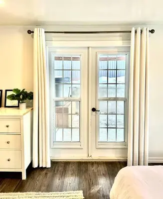 a bedroom with a bed and two windows with curtains at Our Happy Place in Wilberforce