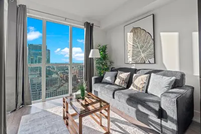a living room with a couch and a large window at 1-Bedroom & Den condo Bird's Eye View in DT in Toronto