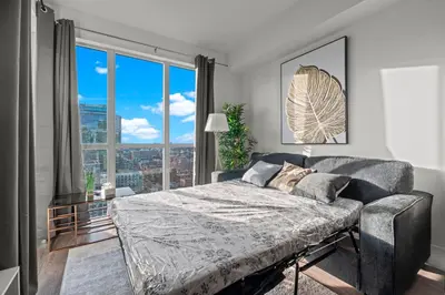 a bedroom with a bed and a large window at 1-Bedroom & Den condo Bird's Eye View in DT in Toronto