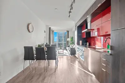 a kitchen with black chairs and red cabinets at 1-Bedroom & Den condo Bird's Eye View in DT in Toronto