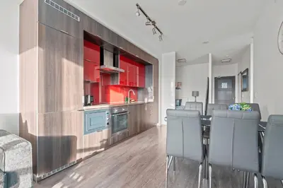 a kitchen with red cabinets and a table and chairs at 1-Bedroom & Den condo Bird's Eye View in DT in Toronto