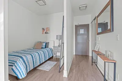 a white bedroom with a bed and a mirror at 1-Bedroom & Den condo Bird's Eye View in DT in Toronto