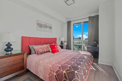 a bedroom with a bed with a red headboard and a window at 1-Bedroom & Den condo Bird's Eye View in DT in Toronto