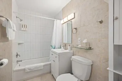 a white bathroom with a toilet and a bath tub at The Wilcox Villa in Mississauga