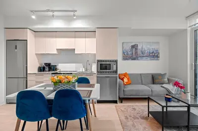 a kitchen and living room with a table and blue chairs at New Modern 1Bd & Den in Downtown Toronto in Toronto