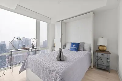 a white bedroom with a bed and a large window at New Modern 1Bd & Den in Downtown Toronto in Toronto