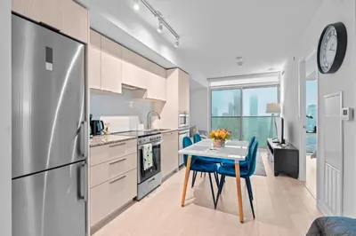 a kitchen with a table and a refrigerator at New Modern 1Bd & Den in Downtown Toronto in Toronto
