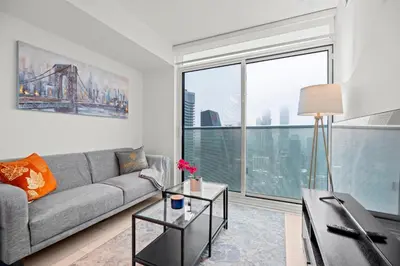 a living room with a couch and a large window at New Modern 1Bd & Den in Downtown Toronto in Toronto