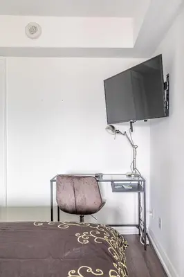 a bedroom with a desk with a television and a chair at Forest 1Bd & DEN in Yorkville 10 Floor in Toronto
