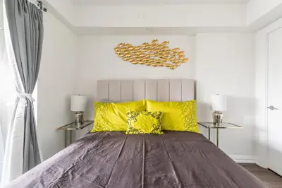 a bedroom with a large bed with yellow pillows at Forest 1Bd & DEN in Yorkville 10 Floor in Toronto
