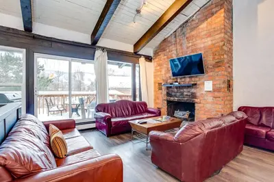 a living room with leather furniture and a brick wall at Happy Daze Big Space Near Village Hot Tub 38L-194 in Blue Mountains