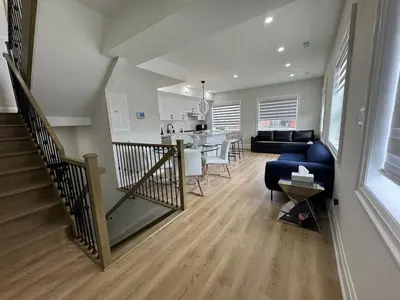 a living room and kitchen with a staircase and a blue couch at Mins from Toronto Downtown UFT Exhibition Place in Toronto