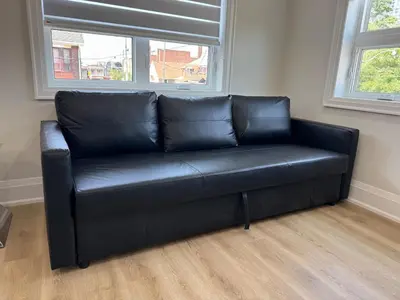 a black leather couch in a room with two windows at Mins from Toronto Downtown UFT Exhibition Place in Toronto