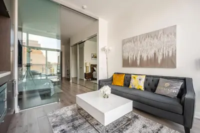 a living room with a black couch and a white coffee table at Gorgeous 1 Bedroom Apt with Balcony in Yorkville in Toronto