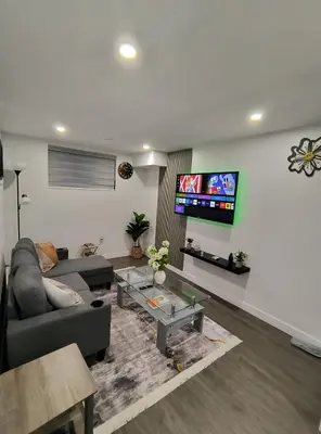 a living room with a couch and a tv on a wall at ArbyManie's Place Newly Built Basement Apartment in London
