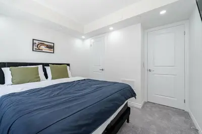 a bedroom with a large bed with a blue blanket at Modern Townhouse Rooftop Vibes in Oakville