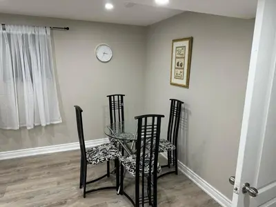 a dining room with a glass table and four chairs at Cozy 1 Bedroom Apartment in Brampton