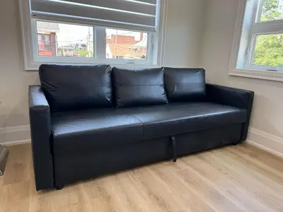 a black leather couch in a room with two windows at Downtown Toronto UFT in Toronto