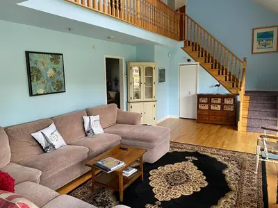 a living room with a couch and a staircase at Beautiful Four Bedroom Lagoon City Waterfront Home in Brechin