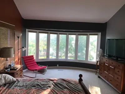 a bedroom with a large window and a pink chair at Beautiful Four Bedroom Lagoon City Waterfront Home in Brechin