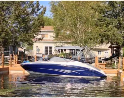 a blue boat sitting in the water in front of a house at Beautiful Four Bedroom Lagoon City Waterfront Home in Brechin