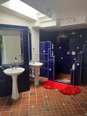a blue tiled bathroom with two sinks and a shower at Fieldstone & Sky in Frankford