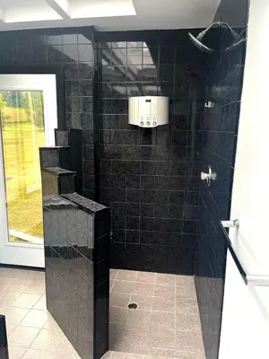 a bathroom with a shower with black tile at Fieldstone & Sky in Frankford