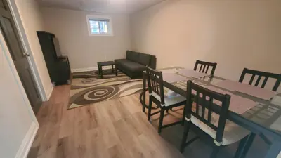 a dining room with a table and chairs and a couch at Cozy Basement Stay in Mississauga in Mississauga