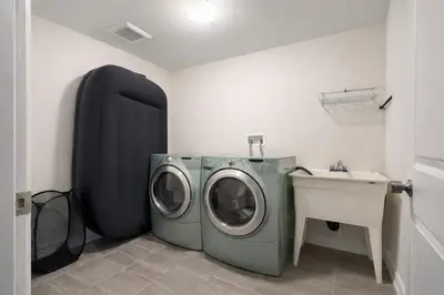 a laundry room with a washing machine and a sink at Central & Cozy 2BR Townhome with Free Parking, WiFi, Full Kitchen, Laundry, Steps to Strip Plaza & 5 Min Drive to Innisfil Beach Park! Perfect for Work Trips, Family Travel & Couples! in Innisfil