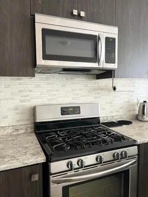 a microwave above a stove in a kitchen at Central & Cozy 2BR Townhome with Free Parking, WiFi, Full Kitchen, Laundry, Steps to Strip Plaza & 5 Min Drive to Innisfil Beach Park! Perfect for Work Trips, Family Travel & Couples! in Innisfil