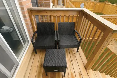 a balcony with two chairs on a wooden deck at Central & Cozy 2BR Townhome with Free Parking, WiFi, Full Kitchen, Laundry, Steps to Strip Plaza & 5 Min Drive to Innisfil Beach Park! Perfect for Work Trips, Family Travel & Couples! in Innisfil