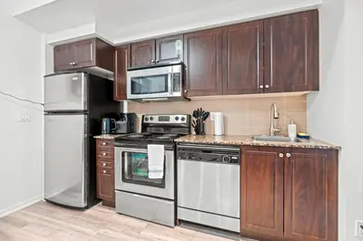 a kitchen with wooden cabinets and stainless steel appliances at Superior 1Bd & DEN Apartment with Balcony in Toronto