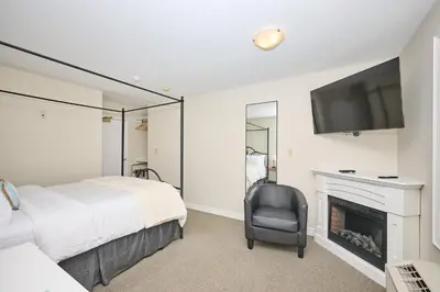 a bedroom with a bed and a television and a chair at Nine Vines Hotel in Niagara on the Lake
