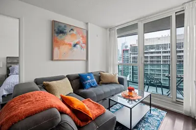 a living room with a couch and a large window at Autumnaly Whisper 2 BR & DEN in the Heart of the City in Toronto