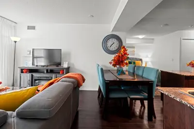 a living room with a couch and a table with a clock at Autumnaly Whisper 2 BR & DEN in the Heart of the City in Toronto