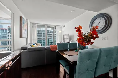 a living room with a couch and a clock on the wall at Autumnaly Whisper 2 BR & DEN in the Heart of the City in Toronto
