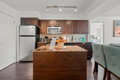 a kitchen with wooden cabinets and a table with flowers on it at Autumnaly Whisper 2 BR & DEN in the Heart of the City in Toronto