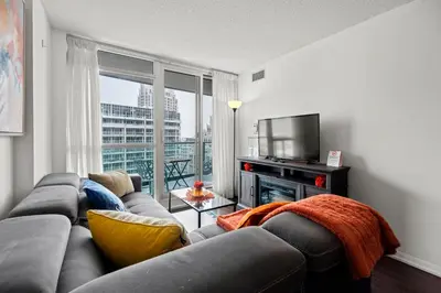 a living room with a couch and a television at Autumnaly Whisper 2 BR & DEN in the Heart of the City in Toronto