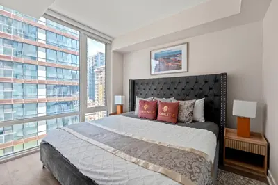 a bedroom with a large bed and a large window at Bright 1BD & Den in Downtown Toronto in Toronto
