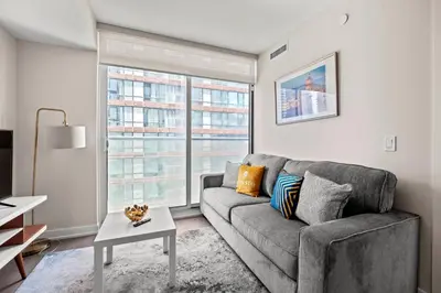 a living room with a couch and a large window at Bright 1BD & Den in Downtown Toronto in Toronto