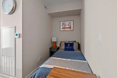 a small bedroom with a bed in a white wall at Bright 1BD & Den in Downtown Toronto in Toronto