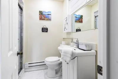 a white bathroom with a toilet and a sink at Muskoka Gem 8ppfireplacescanoekayaks in Bracebridge