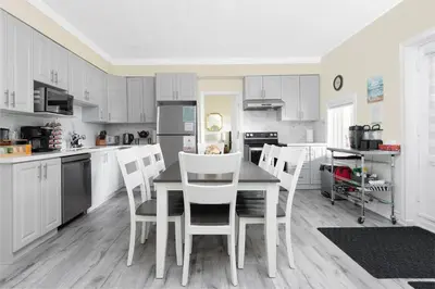 a kitchen with white cabinets and a table and chairs at Muskoka Gem 8ppfireplacescanoekayaks in Bracebridge