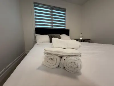 a white bedroom with a bed with towels on it at Upscale Niagara Falls Getaway - BRAND NEW in Niagara Falls