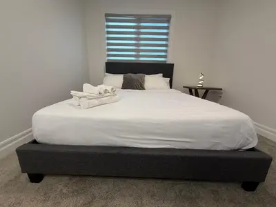 a bedroom with a large white bed with a window at Upscale Niagara Falls Getaway - BRAND NEW in Niagara Falls