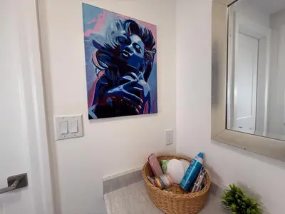 a bathroom with a basket of toothbrushes and a painting at Upscale Niagara Falls Getaway - BRAND NEW in Niagara Falls