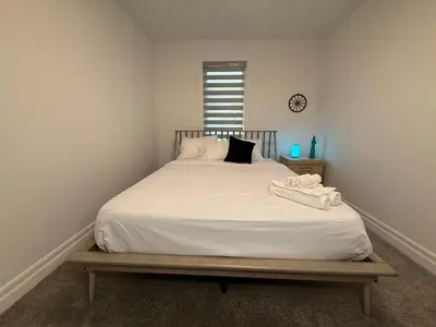 a bedroom with a bed with white sheets and a clock at Upscale Niagara Falls Getaway - BRAND NEW in Niagara Falls