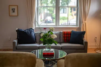 a living room with a couch and a table with flowers at Sun-Filled Century Home in Hamilton