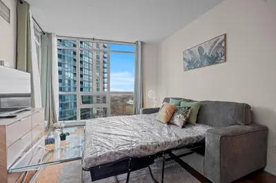 a living room with a couch and a large window at Superior 1Bedroom&DEN Condo with Balcony in Toronto