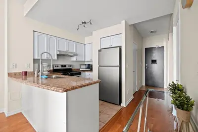 a kitchen with white cabinets and a stainless steel refrigerator at Superior 1Bedroom&DEN Condo with Balcony in Toronto